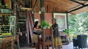 公主港Bambua Nature Cottages的两名妇女站在建筑物的酒吧