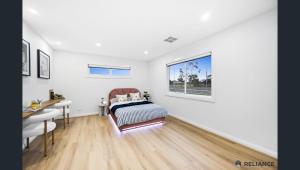 Sunbury home close to Melbourne airport في صَنبري: غرفة نوم بها سرير ومكتب ونافذة