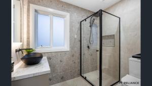 Sunbury home close to Melbourne airport في صَنبري: حمام مع دش زجاجي مع حوض +7 صور