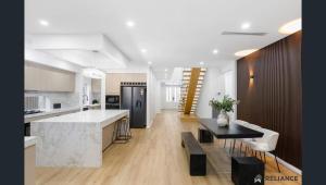 Sunbury home close to Melbourne airport في صَنبري: مطبخ وغرفة معيشة مع كونتر وطاولة