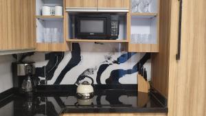 a microwave in a kitchen with a mural on the wall at Jazmin's Apartments in Oranjestad