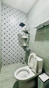 a bathroom with a toilet and a tile wall at Phòng Double View - Chill với Máy Chiếu, Ban Công Xanh Mát in Thôn Trường Giang