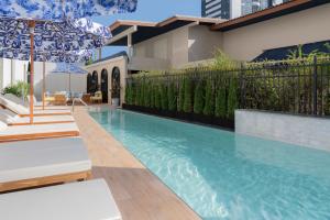 a swimming pool with chairs and an umbrella next to a building at Metropole, Bangkok, a Tribute Portfolio Hotel in Bangkok