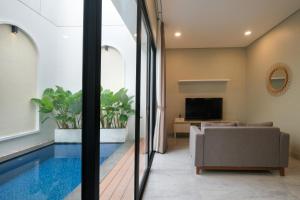 Bellevue Villa Canggu في Pererenan: حمام سباحة في غرفة المعيشة مع أريكة وتلفزيون