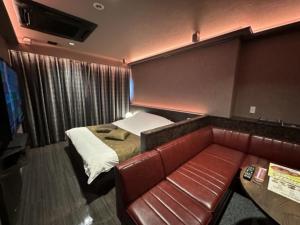 Zimmer mit einem Bett und einem Ledersofa in der Unterkunft HOTEL felice Osaka Itami Airport - Vacation STAY 54182v in Toyonaka