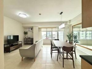 een woonkamer met een tafel, stoelen en een televisie bij Sweethome in Manilla