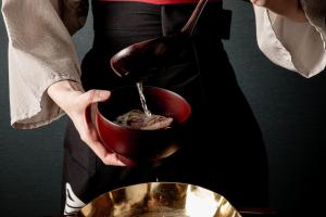 a person is holding a bowl with food in it at Sui Suwako in Suwa