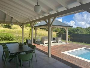 a patio with a table and chairs and a pool at Villa Jade , villa de standing proche de la plage in Le Vauclin