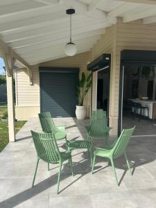 four green chairs and a table on a patio at Villa Jade , villa de standing proche de la plage in Le Vauclin +18 photos