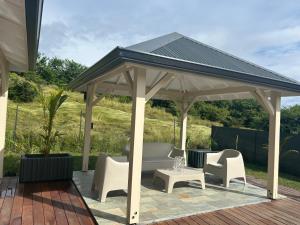 a pavilion with chairs and a table on a deck at Villa Jade , villa de standing proche de la plage in Le Vauclin