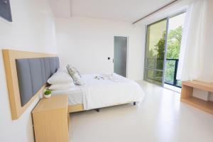 ein weißes Schlafzimmer mit einem Bett und einem großen Fenster in der Unterkunft Aqua Luna Dhangethi in Dhangethi