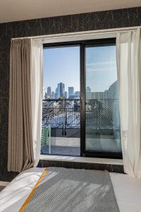 a bedroom with a window with a view of a city at Mi-Hotel Kitashinjuku 北新宿 in Tokyo