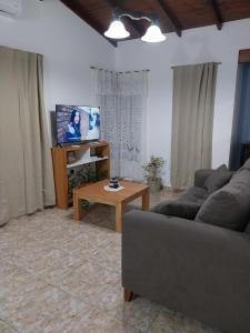 ein Wohnzimmer mit einer Couch, einem Tisch und einem Fernseher in der Unterkunft Refugio entre el Lago y el Mar in Mar de Cobo