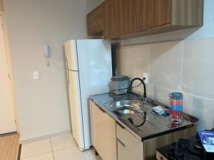 a kitchen with a sink and a white refrigerator at Apto moderno e aconchegante in Ponta Grossa