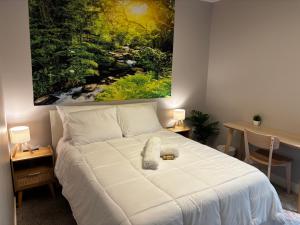 a bedroom with a white bed with a painting on the wall at Nature Home Near Downtown and 17th Avenue in Calgary