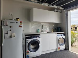 a kitchen with a washing machine and a refrigerator at Hosts on the Coast Skippers Landing in Whitianga