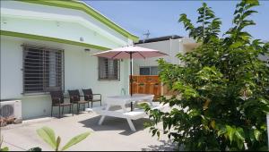 un patio con una mesa blanca y una sombrilla en Green Lodge, en Yomitan