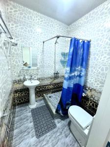 ein Badezimmer mit blauem Duschvorhang und Toilette in der Unterkunft Sunnat guest house in Buxoro