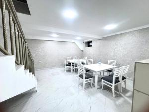ein Esszimmer mit weißen Tischen und Stühlen in der Unterkunft Sunnat guest house in Buxoro + 21 Fotos