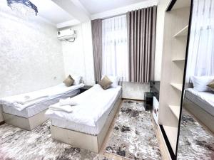 ein Hotelzimmer mit zwei Betten und einem Spiegel in der Unterkunft Sunnat guest house in Buxoro