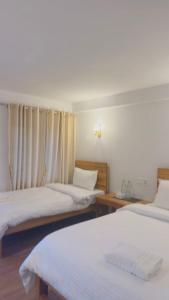 a room with three beds and two tables and curtains at RJ Boutique Hotel - Ghandruk in Astam