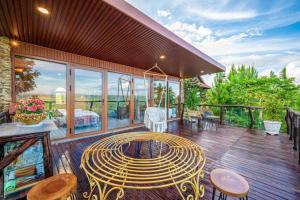 a wooden deck with a table and chairs on it at Hilltop Valley Lâm Đồng in Di Linh