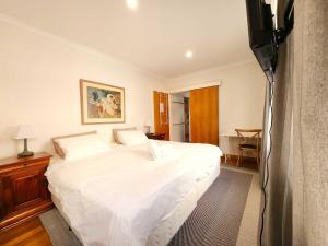 a bedroom with a large white bed and a television at Large king guest room with walking in robe and free parking in Highett