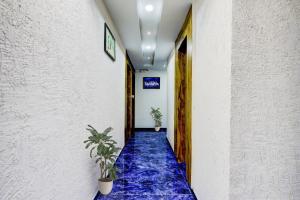 ein Flur mit blauem Teppich und zwei Topfpflanzen in der Unterkunft Hotel O Bhavy in Ahmedabad