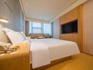 una camera da letto con un grande letto bianco e un divano di JI Hotel Chengdu Tianfu Square a Chengdu