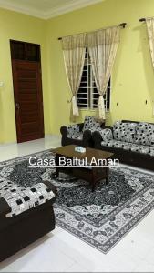 a living room with black couches and a rug at Casa Baitul Aman in Kuala Terengganu
