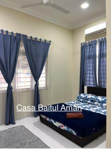 a bedroom with a bed with blue curtains and a window at Casa Baitul Aman in Kuala Terengganu