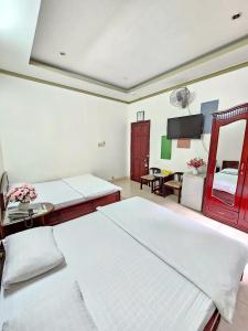 芹苴Thanh Tùng Hotel的有两张床和一张桌子的大房间