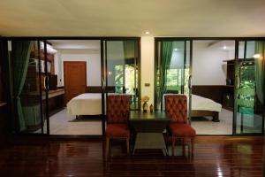 a room with a table and two chairs and a bed at BaanPranwadee in Ban Na Kai