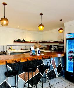 a kitchen with a bar with chairs and a refrigerator at Casa Maya Guesthouse in Mal País