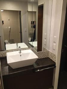 柏市にあるホテルリンクス柏市豊四季店の白い洗面台と鏡のあるバスルーム