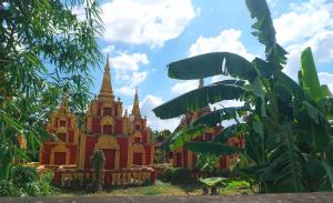 een tempel met steile torens in een veld met een boom bij Roza Guest House in Kampot +6 foto's