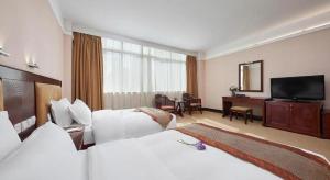 a hotel room with two beds and a flat screen tv at Cheerful Hotel in Nanhai
