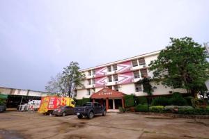 ein großes Gebäude mit auf einem Parkplatz abgestellten Autos in der Unterkunft PC Palace Hotel in Sakon Nakhon