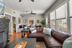 a living room with a brown leather couch and a fireplace at Be A Nomad - Historic 6BR Cottage Steps to Jacksonville Beach Sleeps 12 in Jacksonville Beach +28 photos