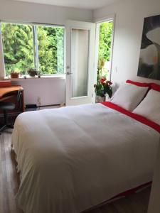 1 dormitorio con 1 cama blanca grande y 2 ventanas en A Room at the Camelia Bed and Breakfast en Tsawwassen