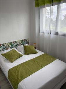 Grande villa avec piscine et spa في Longages: غرفة نوم بسرير أبيض كبير مع وسائد خضراء +46 صورة