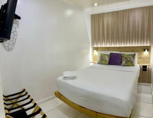 a bedroom with a white bed and a chair at Jazmin's Apartments in Oranjestad
