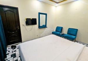 a room with two blue chairs and a bed and a mirror at Hayat Lodges & Hotel in Lahore +59 photos