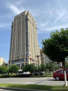 a large building with a red car parked in front of it at Xana Hotelle Chengdu Dafeng Huirong Plaza Longhu Street in Chengdu