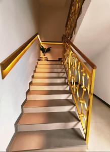 Una escalera con barandilla dorada y una planta en maceta. en Parays Fernwoods, en Mannārakkāt