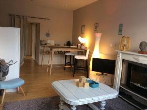 Kosy Suite في Saint-Aubin-du-Cormier: غرفة معيشة مع طاولة أمام موقد