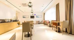 a dining room with tables and chairs and a kitchen at City Comfort Inn Nanning Wuming Lijian in Wuming