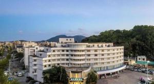 ein großes weißes Gebäude mit einem Parkplatz in der Unterkunft City Comfort Inn Lingshui Central Avenue Bus Station in Lingshui