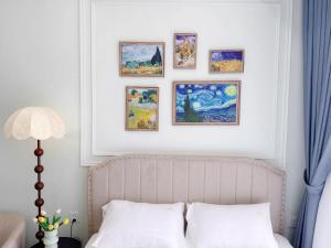 a bedroom with a bed and framed paintings on the wall at Studio Apt OceanPark in Kon Rung (1) +1 photo