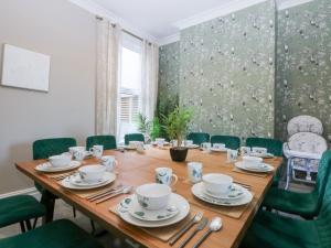 a dining room with a wooden table and green chairs at Canning Lodge in Colwyn Bay